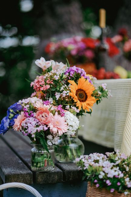 A bouquet arrangement featuring a variety of fresh flowers including a prominent sunflower with bright yellow petals and a dark center, surrounded by pink, purple, and white blossoms such as daisies,