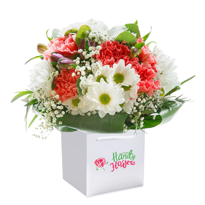 Expertly arranged and set against a crisp, white canvas, this contemporary floral bouquet from Gidea Park radiates warmth and vitality. Hashed with full-bodied coral and deep peach carnations-each nestled petal reminiscent of joyous gatherings by local cafes-this bouquet grounds its blend of colour in softness and abundance. The addition of luminous white daisies with vibrant lime-green centers infuses an energy that echoes children's laughter in Raphael Park, while tender sprays of baby's breath drift throughout, their snowy blossoms lending a whimsical, feathery finish. Here and there, subtle purple-tinged flower buds peep from within, giving subtle depth and an air of anticipation. Wrapping the base, generous arcs of bold green leaves provide sturdiness and style, their glossy sheen reflecting afternoon sunlight over Gidea Park's tranquil streets. Satin ribbon handles create an inviting feel, ready for same-day delivery across the neighbourhood-whether for marking a milestone, celebrating a birthday, or simply letting someone know they're cherished. The bouquet's sculpted, rounded silhouette and perfectly balanced palette capture the heart of local floristry: a marriage of beauty, care, and the unique community spirit that defines Gidea Park.