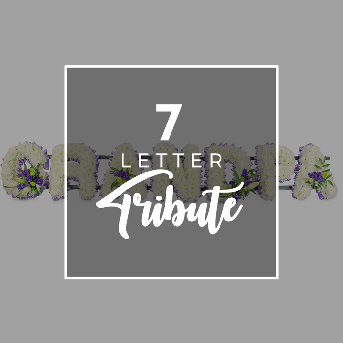 This thoughtfully composed image uses a smooth, grey background to set a calm, neutral tone, making the central dark grey square stand out like a neatly printed sign. The square is lined with a fine white border and holds white text that reads 7 LETTER Tribute. The numeral 7 is bold and prominent, LETTER appears in understated uppercase sans-serif letters just below, and Tribute is rendered in a soft, flowing script that brings a touch of warmth and humanity to the design. Behind this central square, partly hidden yet clearly identifiable, lies a bespoke floral letter tribute spelling GRANDAD, the sort of personalised piece often chosen for funerals in and around Gidea Park. Each letter is densely packed with pure white chrysanthemums or similar small-headed flowers, the tightly layered petals forming a smooth, rounded surface that looks plush to the touch, like a cushion of blooms. Carefully placed clusters of rich purple flowers and sprigs of fresh green foliage nestle within the white base, adding depth and contrast while preserving an overarching sense of calm and dignity. On the left, the open curve of the initial G and the diagonal line of the R extend from beneath the square, while on the right, glimpses of the final A and D suggest the completed word. The overall impression is of a lovingly considered, seven-letter funeral tribute, crafted to remember a cherished grandad with flowers that reflect both respect and affection. It feels like the kind of arrangement a local Gidea Park florist would create to be placed beside a coffin or at the front of a chapel, allowing family and friends to see a familiar name represented in fresh blooms.